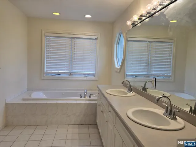 a bathroom with a granite countertop sink a large mirror and a bathtub