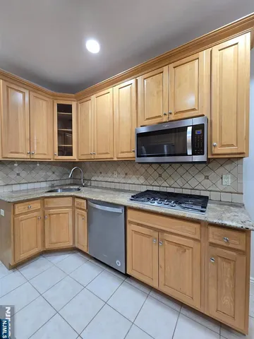 a kitchen with granite countertop cabinets stainless steel appliances a sink and a large window