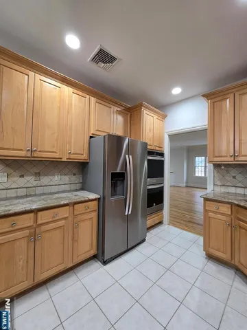 a kitchen with stainless steel appliances granite countertop a refrigerator and a stove top oven