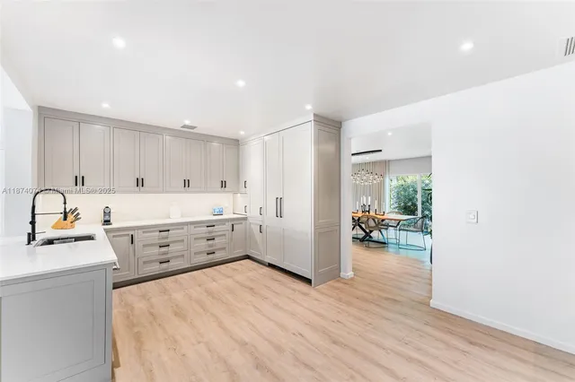 a kitchen with stainless steel appliances a stove top oven a sink a refrigerator and white cabinets with wooden floor