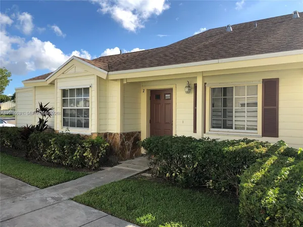 a view of a house with brick walls and a yard with plants