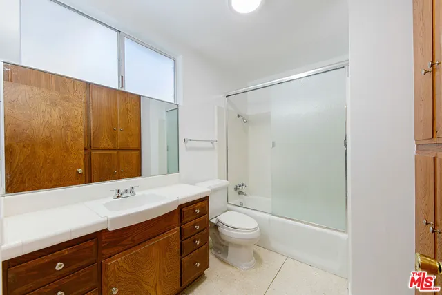 a bathroom with a double vanity sink toilet mirror and shower