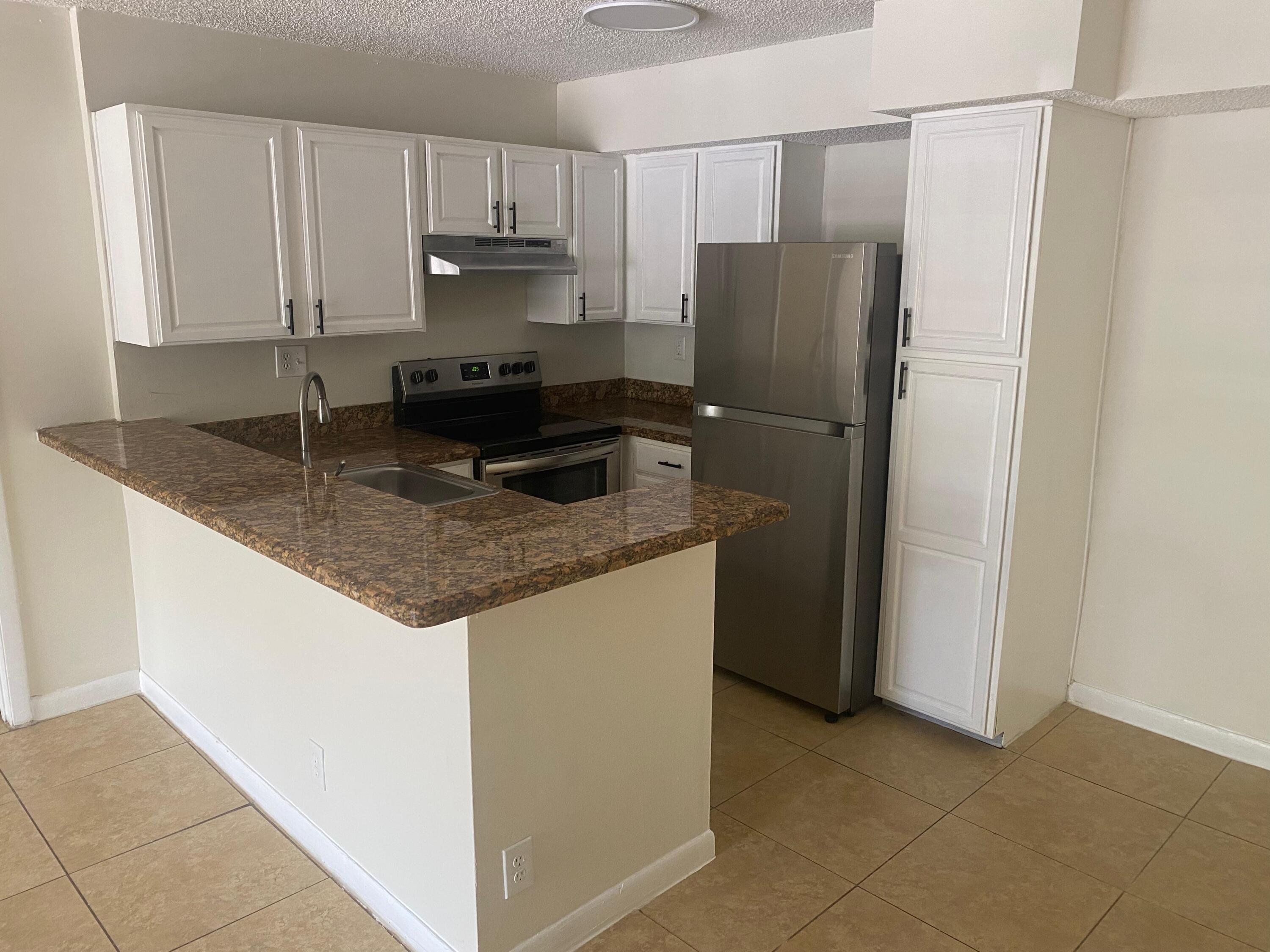 601 Lyons Road, Unit 7105 Coconut Creek, FL 33063 - Photo 1 of 13 a kitchen with granite countertop a refrigerator and a stove top oven