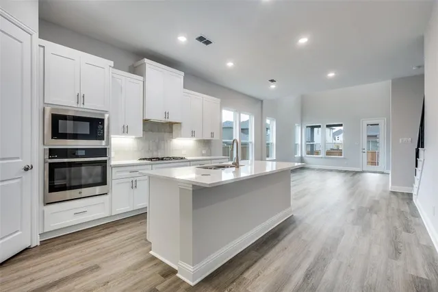 a large kitchen with stainless steel appliances kitchen island granite countertop a stove a sink and a refrigerator