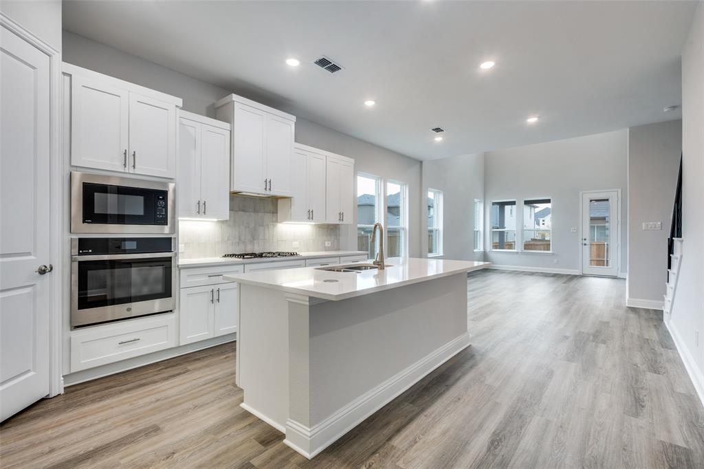11764 Chartwell Court Frisco, TX 75035 - Photo 5 of 25 a large kitchen with stainless steel appliances kitchen island granite countertop a stove a sink and a refrigerator
