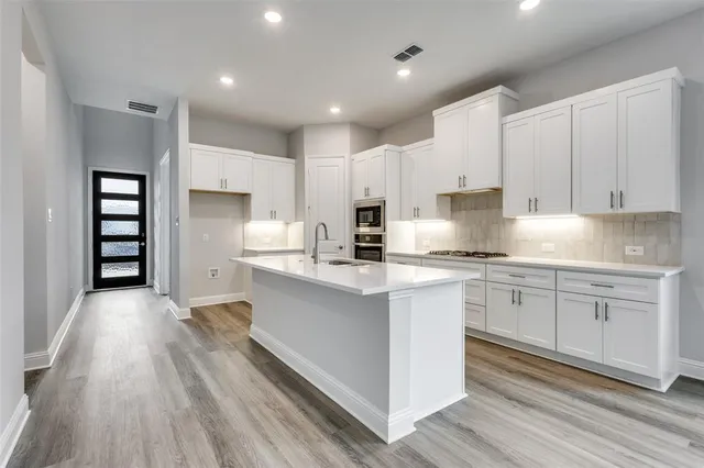 a kitchen with kitchen island granite countertop a sink cabinets and stainless steel appliances