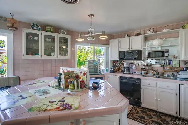 a kitchen with a stove a sink dishwasher a dining table and chairs with wooden floor