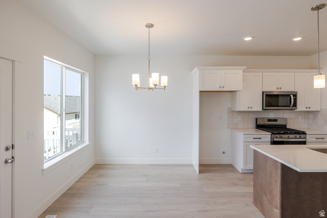 4748 Heartwood Road, Unit 434 Mapleton, UT 84664 - Photo 10 of 18 Kitchen with stainless steel appliances, light wood-style flooring, tasteful backsplash, a chandelier, and light stone countertops