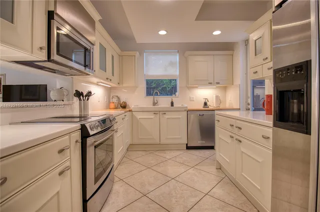 a kitchen with stainless steel appliances granite countertop a sink and dishwasher a stove top oven with white cabinets
