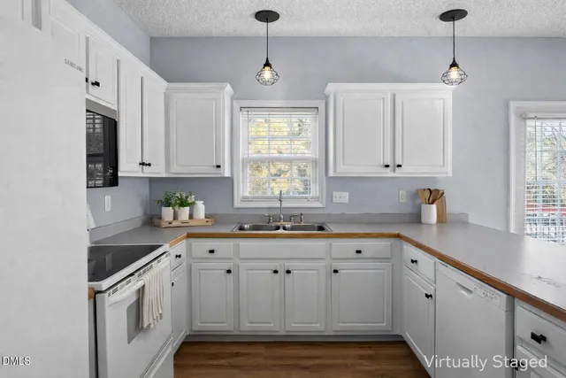 a kitchen with granite countertop white cabinets white appliances and a window