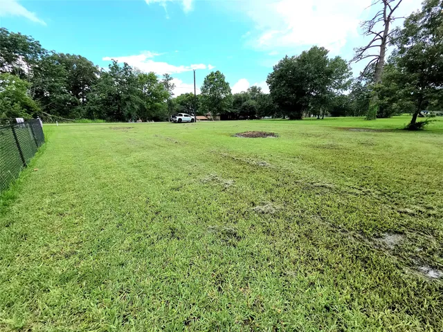 a view of a green field with trees in the background
