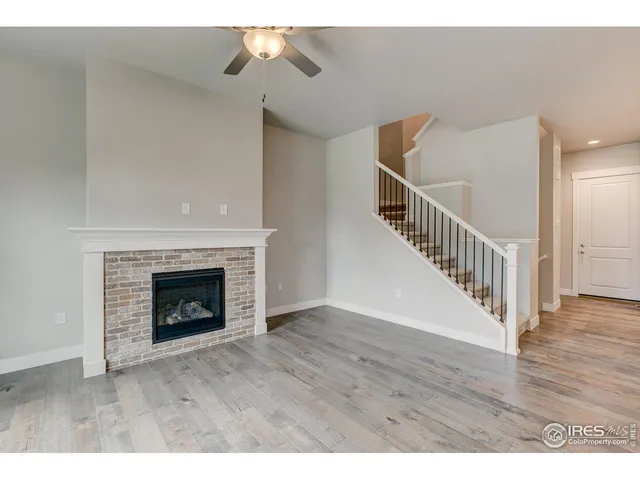 a view of an empty room with wooden floor and a fireplace