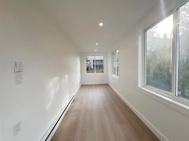 a view of a big room with wooden floor and windows