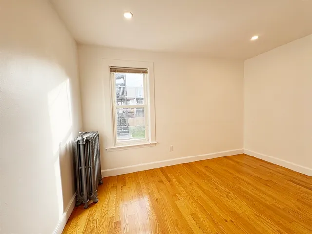 an empty room with wooden floor and a window