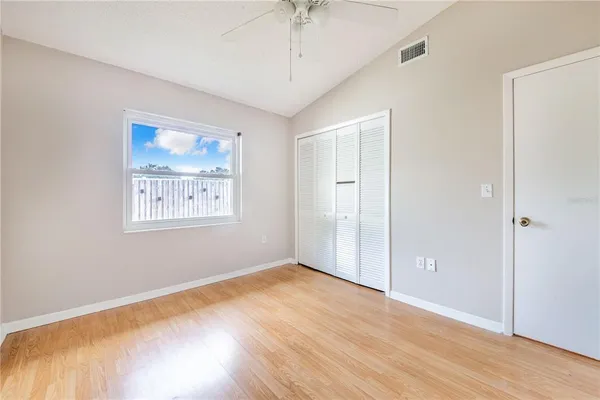 an empty room with wooden floor chandelier fan and windows