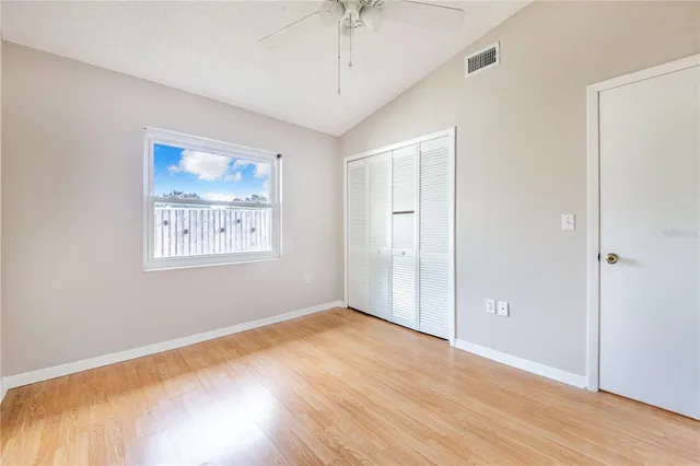 an empty room with wooden floor chandelier fan and windows
