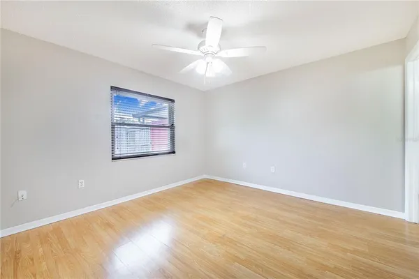 an empty room with wooden floor ceiling fan and windows