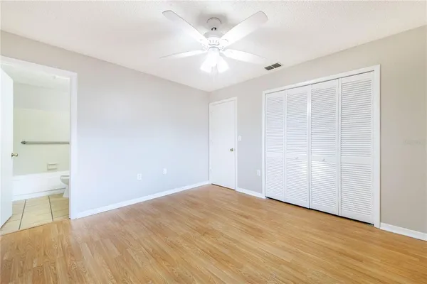 an empty room with wooden floor and a ceiling fan