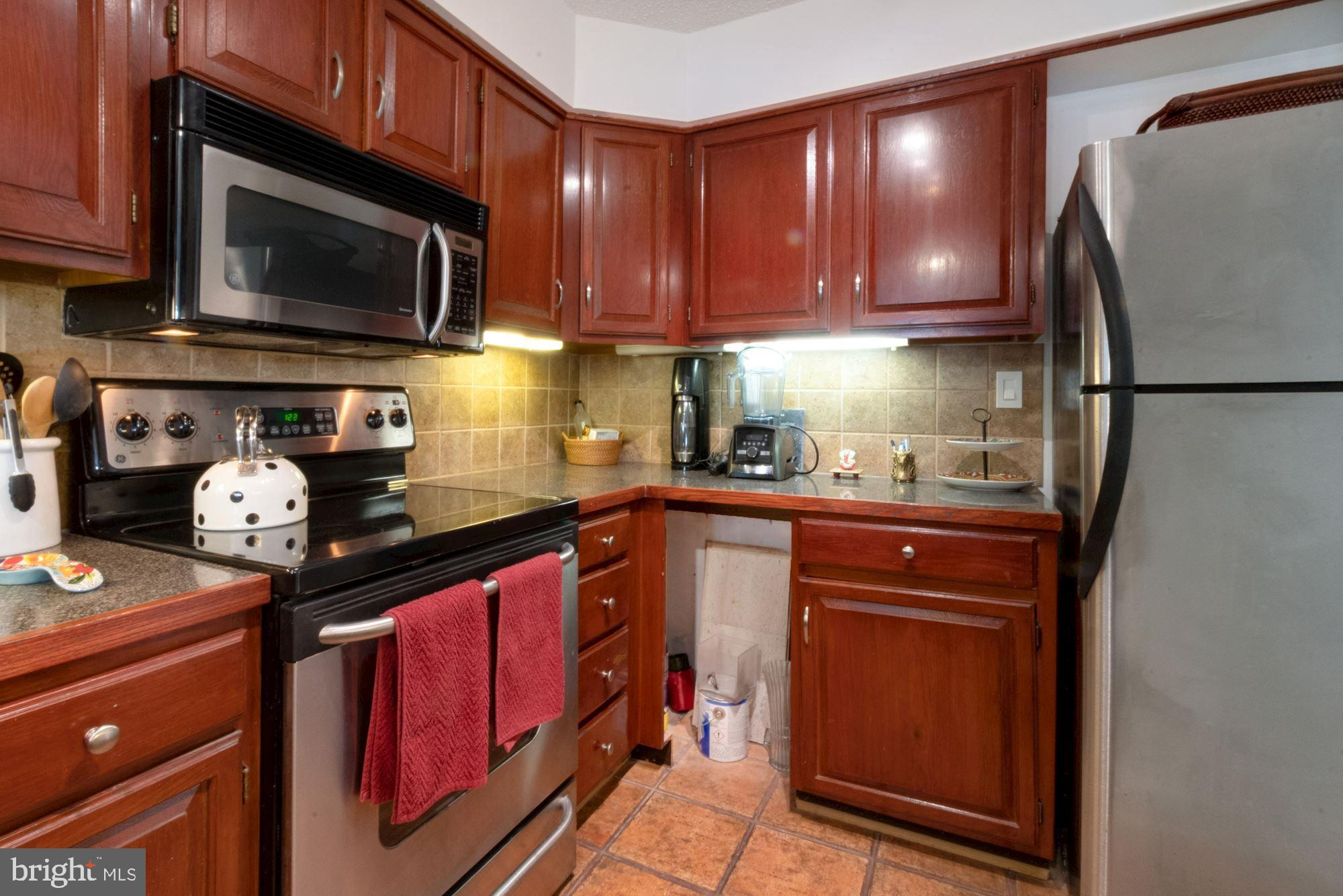 1080 Wisconsin Avenue Northwest, Unit 405 Washington, DC 20007 - Photo 14 of 31 a kitchen with stainless steel appliances granite countertop a refrigerator stove and microwave