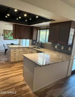 a view of a kitchen with kitchen island a sink wooden floor and counter space