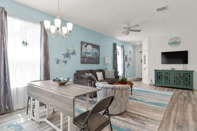a living room with furniture a flat screen tv and a chandelier