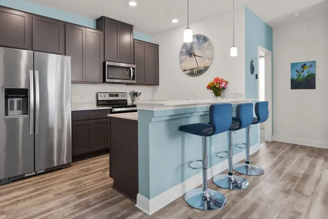 a kitchen with granite countertop a table chairs stove and refrigerator