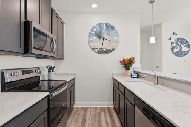 a spacious kitchen with stainless steel appliances a sink and a refrigerator