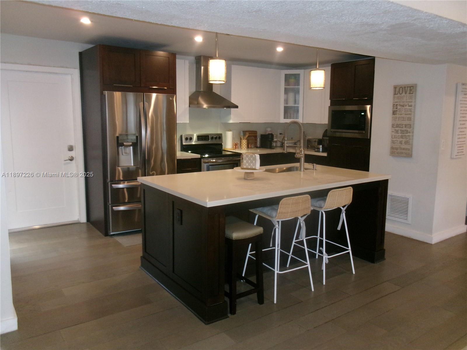 11430 Southwest 83rd Terrace Miami, FL 33173 - Photo 7 of 19 a kitchen with stainless steel appliances a table chairs refrigerator and microwave