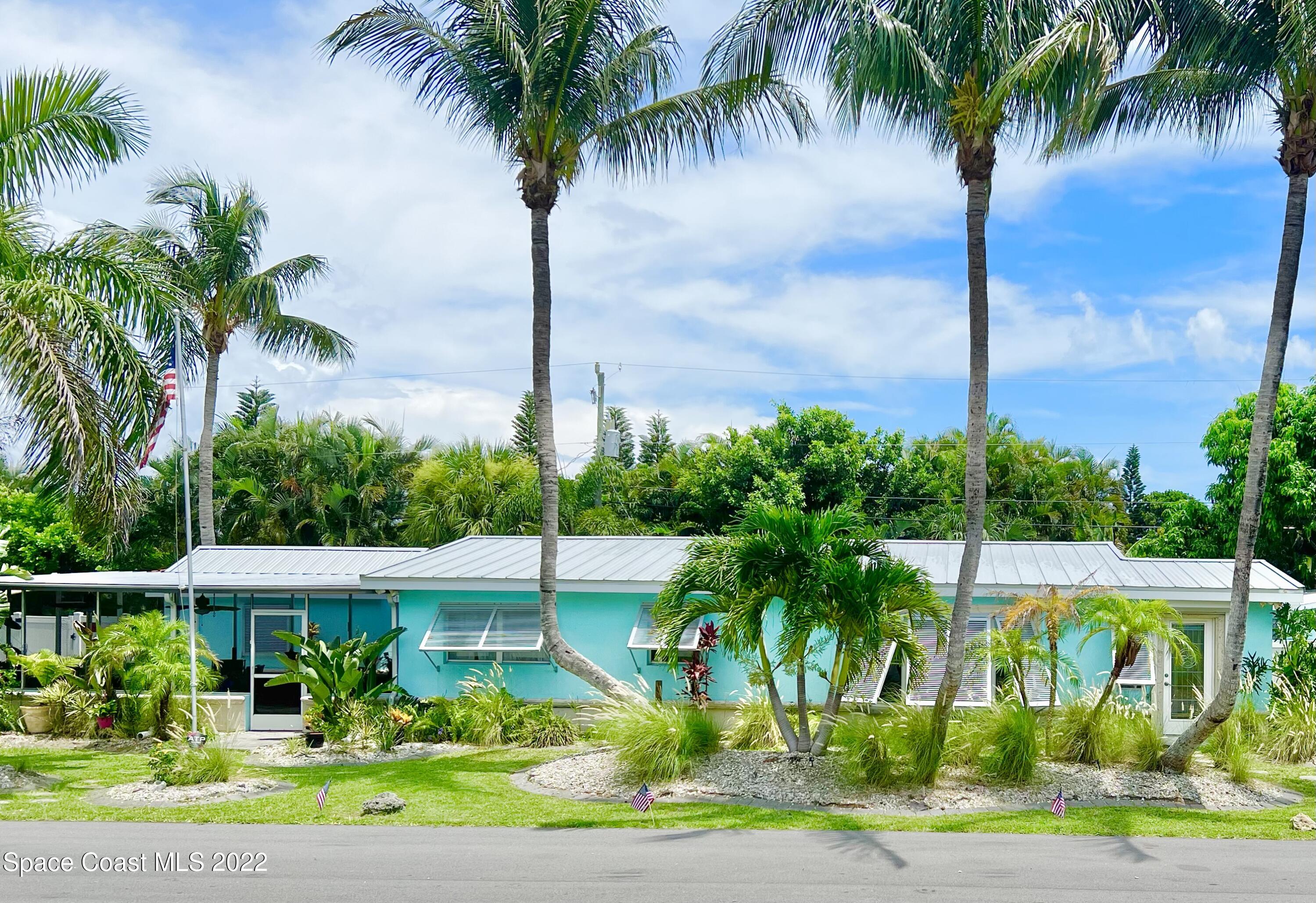 a view of a palm tree in front of a house with a yard