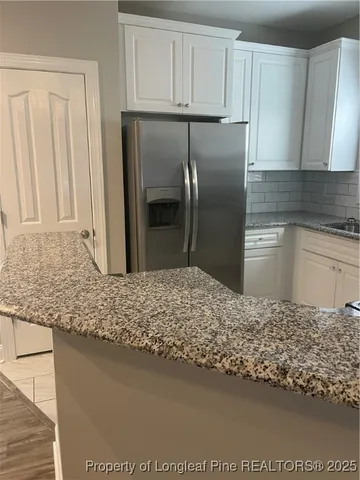 a kitchen with kitchen island granite countertop a refrigerator and a sink