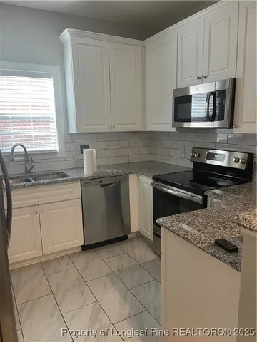 a kitchen with stainless steel appliances granite countertop a sink stove top oven and microwave