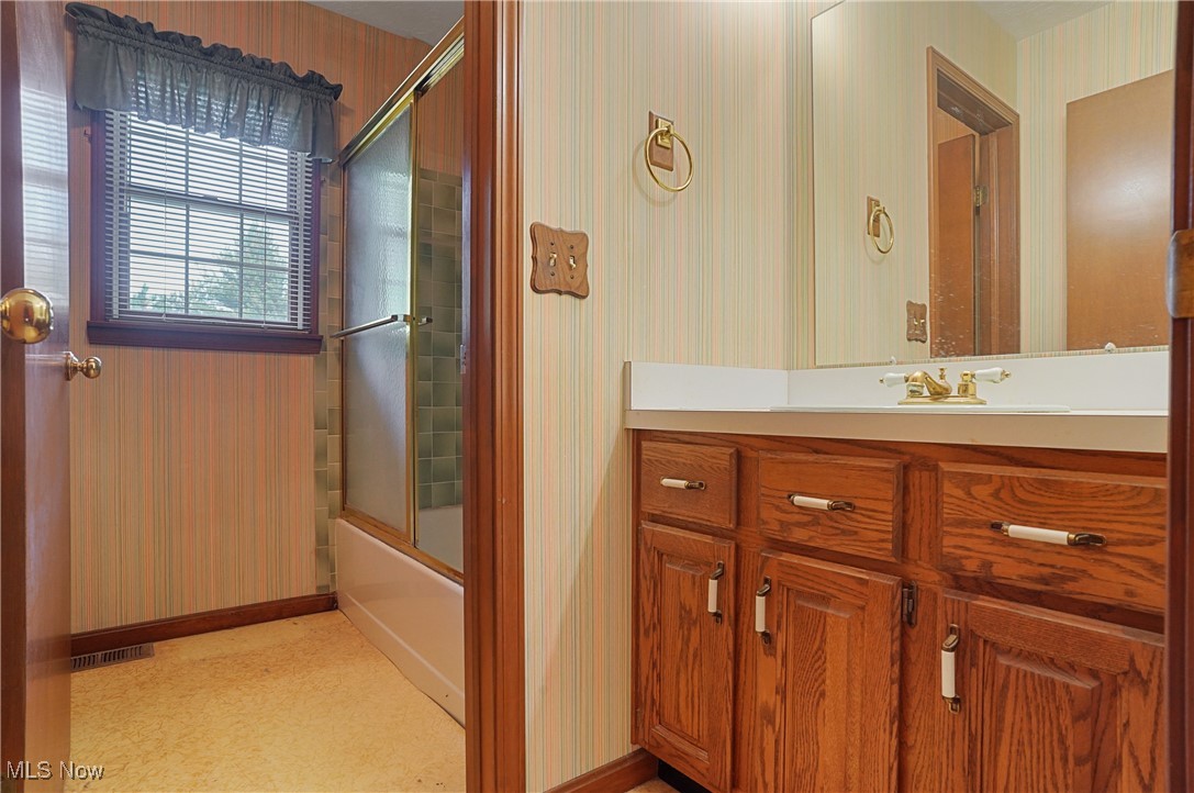 7300 Morley Road Painesville, OH 44077 - Photo 32 of 50 Full bathroom featuring bath / shower combo with glass door, wallpapered walls, and vanity