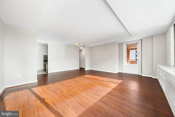 a view of an empty room with wooden floor and a window