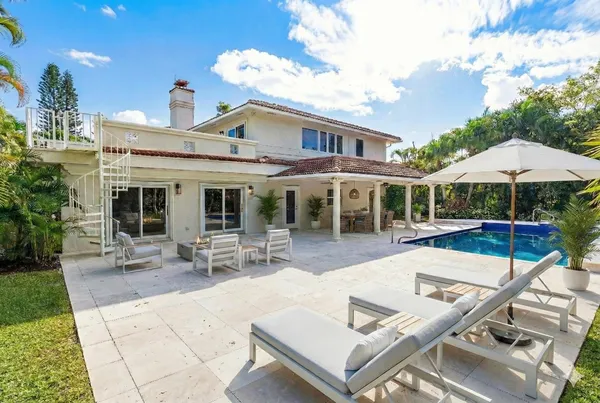 a view of a house with backyard sitting area and swimming pool