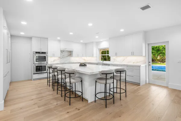 a kitchen with stainless steel appliances a dining table chairs and wooden floor