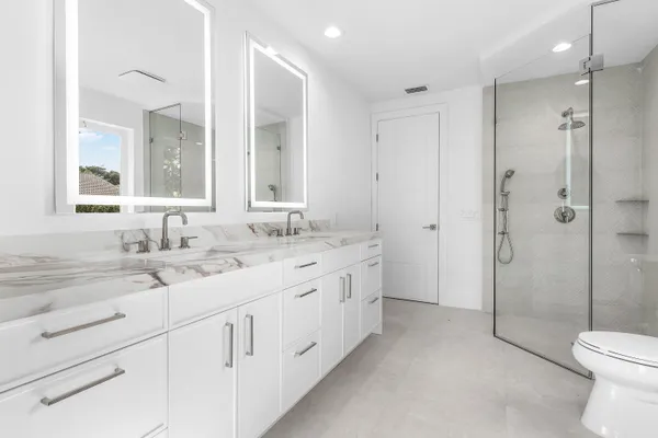 a bathroom with a double vanity sink toilet and shower