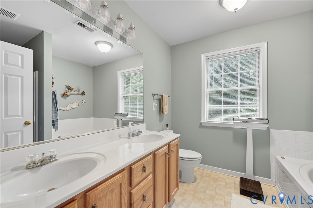 3420 Osborne Road Chester, VA 23831 - Photo 31 of 36 a spacious bathroom with a granite countertop sink a toilet and a large mirror