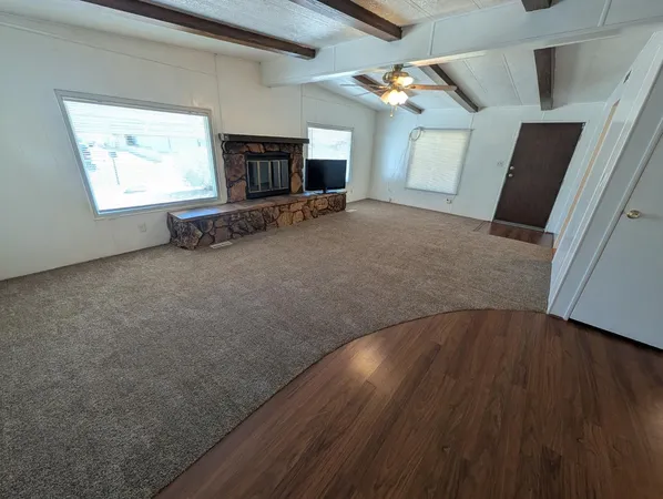 an empty room with wooden floor fireplace and windows