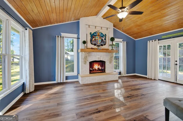 a view of an empty room with wooden floor fireplace and a window