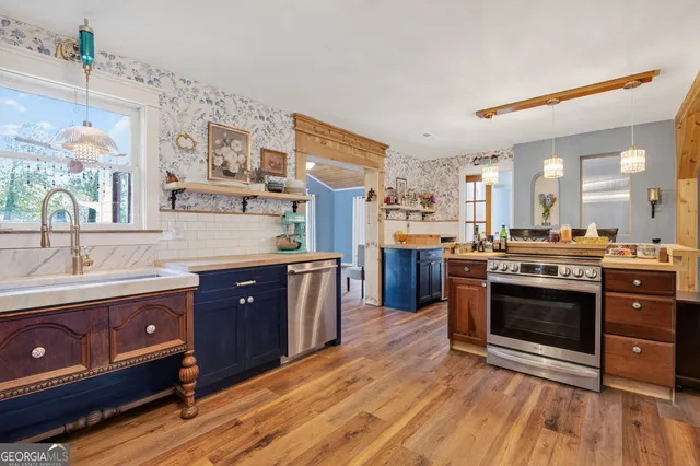 a large kitchen with stainless steel appliances granite countertop a stove and a wooden floors