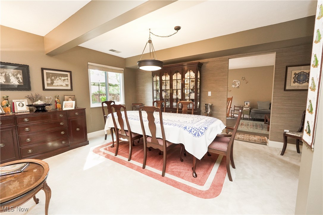 Dining room with beam ceiling and light colored carpet