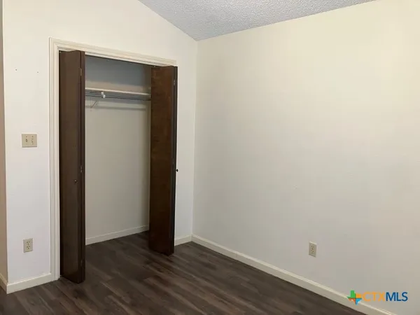 a view of an empty room with wooden floor and closet