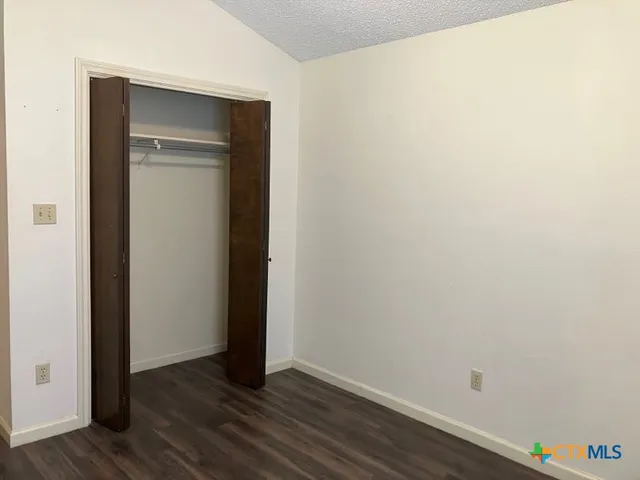 a view of an empty room with wooden floor and closet