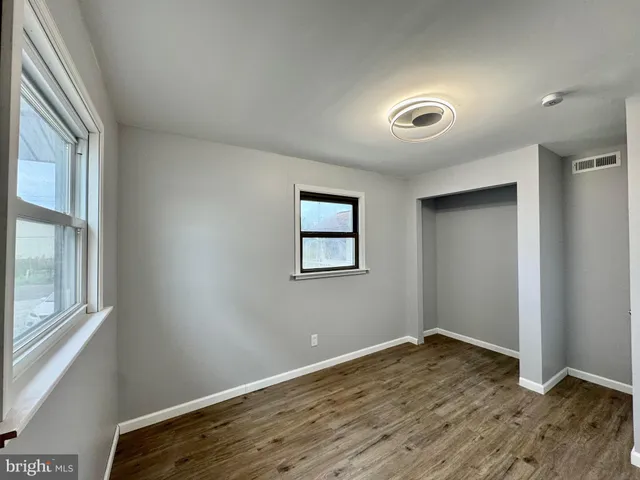 a large kitchen with stainless steel appliances wooden floors wooden cabinets a sink and a window