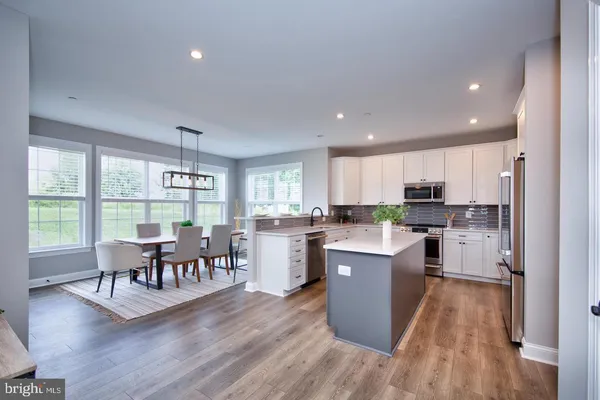 a living room with furniture wooden floor and a kitchen view