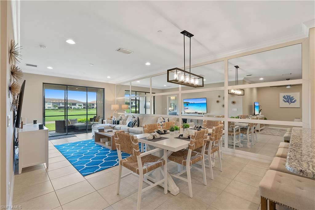 a living room with lots of tables a large window and a chandelier