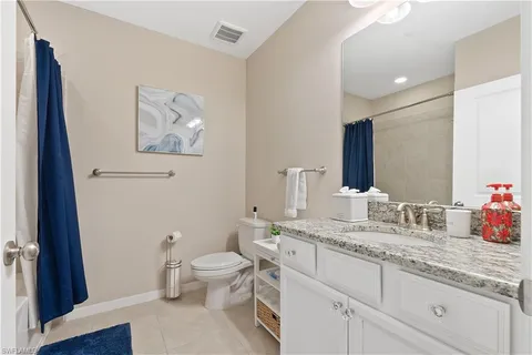 a bathroom with a granite countertop sink mirror vanity and toilet
