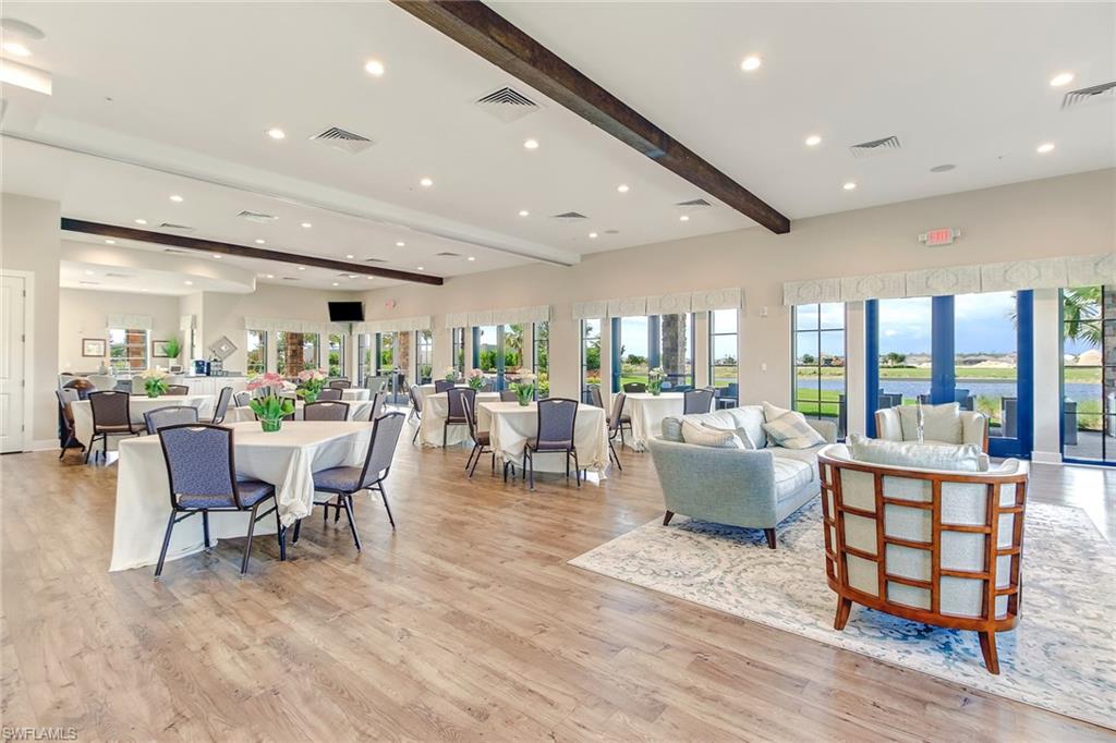 9386 Pocida Court, Unit 103 Naples, FL 34119 - Photo 41 of 43 a dining room with furniture wooden floor and a floor to ceiling window