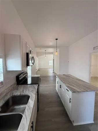 a kitchen with granite countertop a refrigerator and a sink