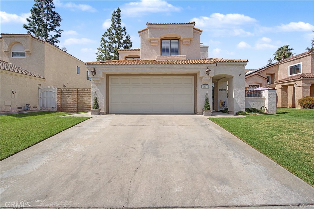 1129 Vía Nice Redlands, CA 92374 - Photo 2 of 23 a front view of a house with a yard and garage